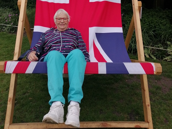 Janet with a big smile sitting in an oversized Union Jack deckschair, taken by her volunteer Move Mate