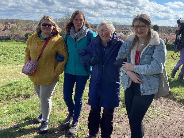 Four women smiling on a walk with volunteers.