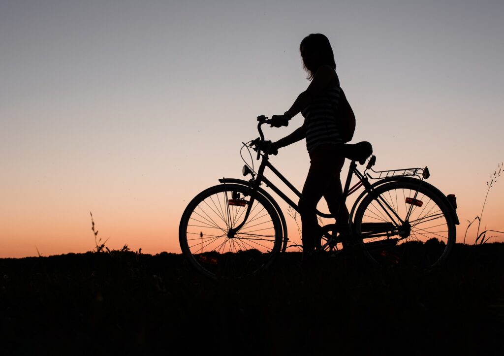 Photo of woman and bike in silhouette with sunset behind