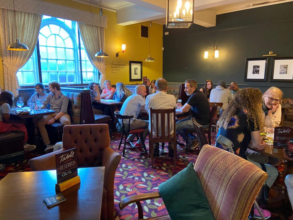 People sat around tables in pub, quizzing